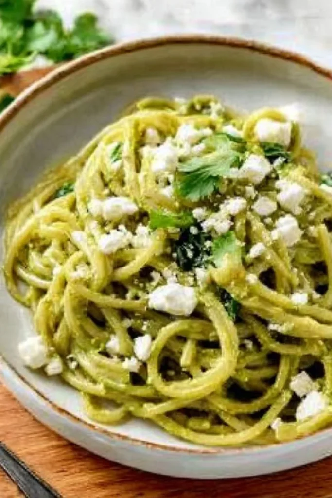 Plate of flavorful Mexican green spaghetti garnished with green sauce and herbs