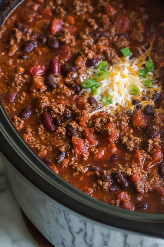 Delicious bowl of slow cooker beef chili topped with fresh herbs.