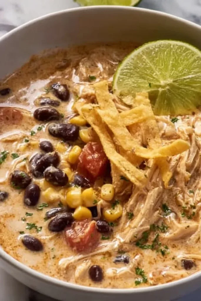 Crockpot White Chicken Chili with Cream Cheese in a bowl garnished with herbs