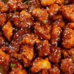 Crispy sesame chicken garnished with sesame seeds and green onions