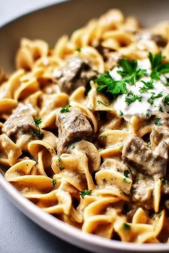 Cozy slow cooker beef stroganoff topped with fresh parsley in a bowl.