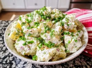 Creamy sour cream potato salad served in a bowl with fresh herbs