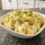 Creamy potato salad in a bowl, garnished with herbs for a picnic dish