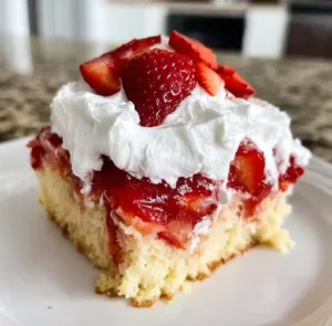 Delicious Strawberry Shortcake Poke Cake topped with fresh strawberries and whipped cream.